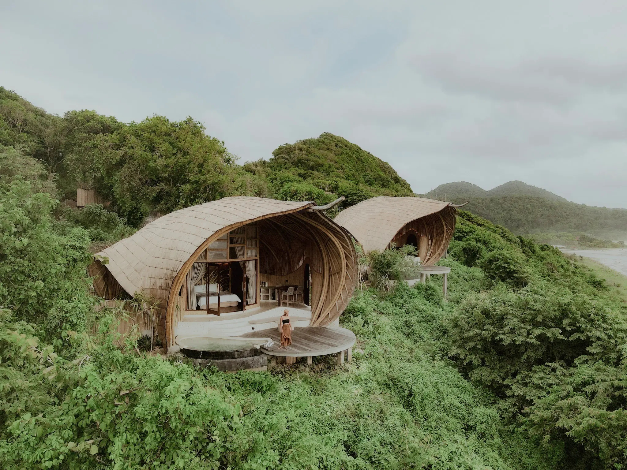 Aerial drone view of Eco Bamboo Beach View Lodge overlooking the Indian Ocean and jungle hills — Kini Resort Sumbawa